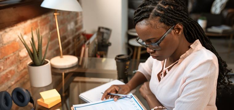 businesswoman at desk filling out paperwork 