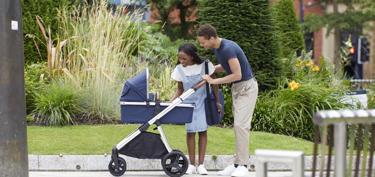 Couple smiling at their baby in a pram in a park