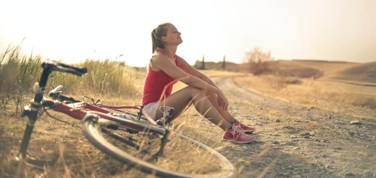 Woman sitting on the ground near a bicycle