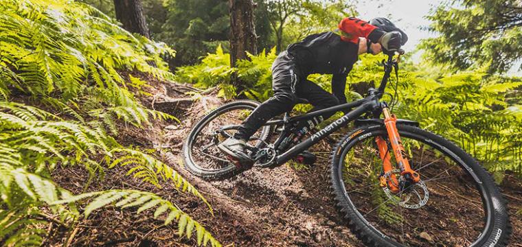 Man riding an Atherton's mountain bike through woodland trail. 