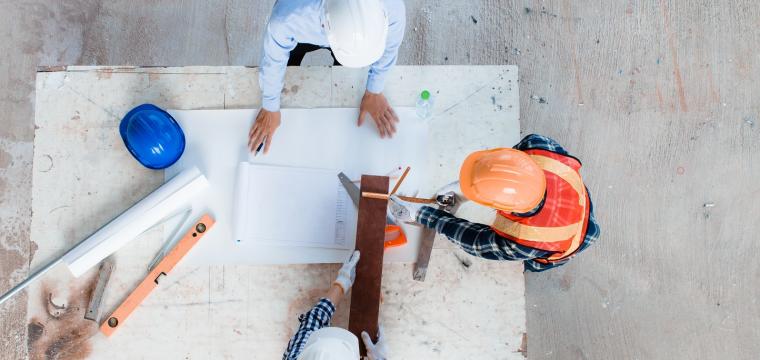 Property developers designing, planning, measuring layout of building blueprints in construction site