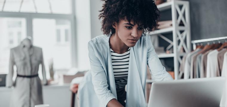 business owner in clothes workshop looking at laptop 