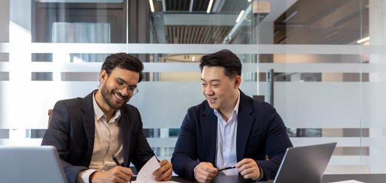 Two men sitting by a laptop