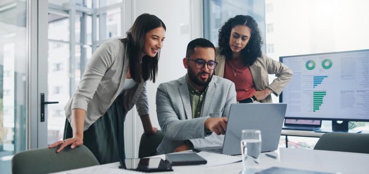 Three colleagues discussing work on one computer