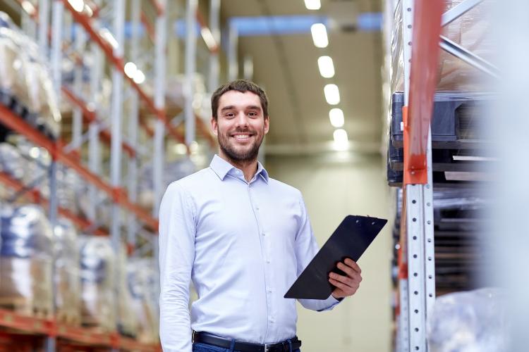 man with tablet in warehouse smiling at camera 