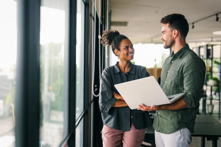 Two colleagues discussing work on a laptop