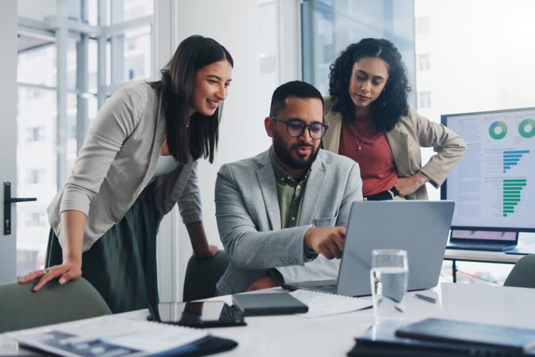 Three colleagues discussing work on one computer